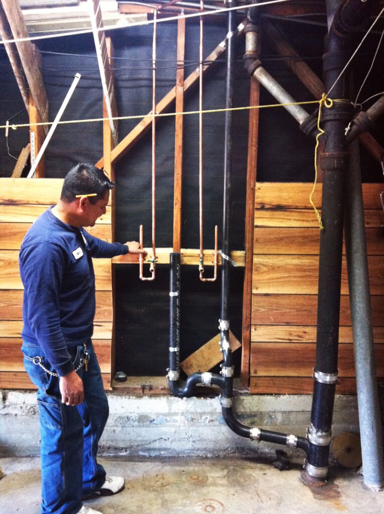 Man inspecting newly installed plumbing service in a building under construction.